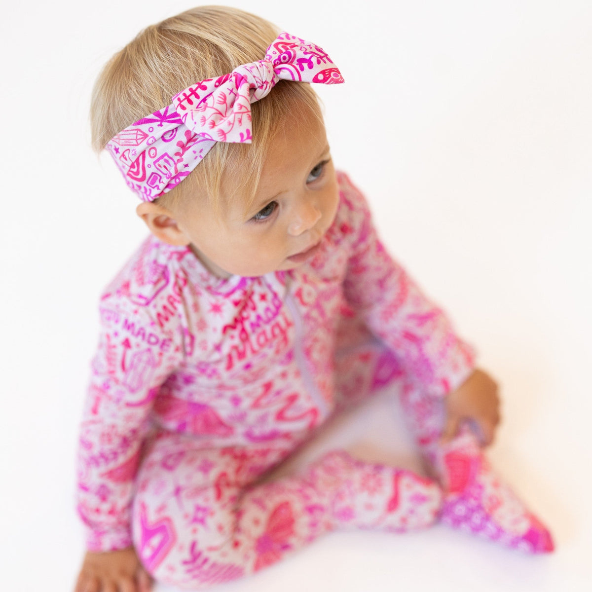 Baby wears The SoftKnot Bow Mystic Mama Pink bamboo head-wrap bow with cozy, non-scratch fit.