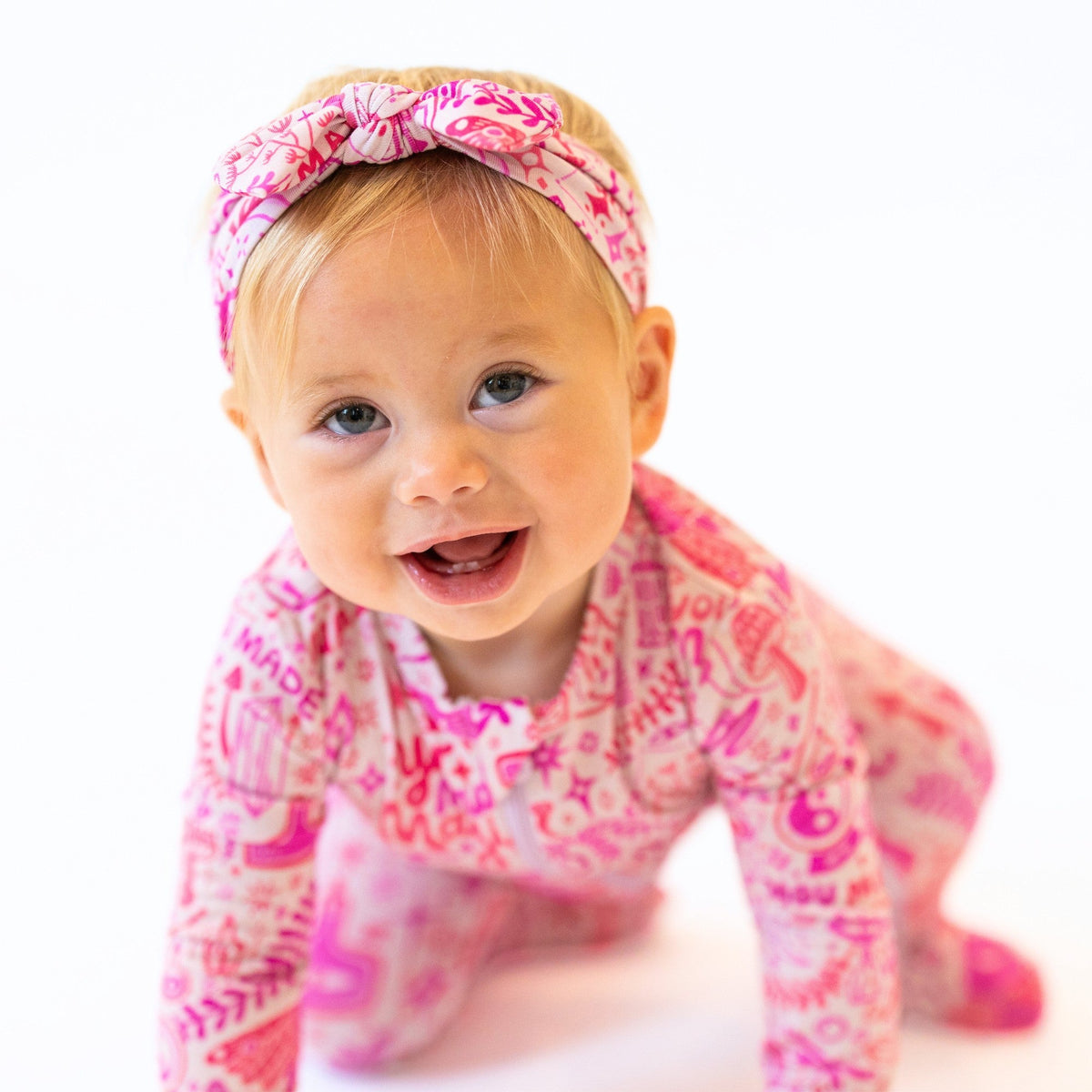 The SoftKnot Bow Mystic Mama Pink head-wrap on a smiling baby.