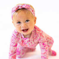 The SoftKnot Bow Mystic Mama Pink head-wrap on a smiling baby.