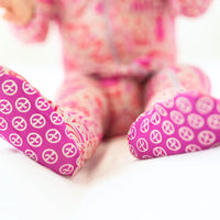 The Second-Skin Bamboo Zippered Footie | Mystic Mama artistically presented among baby accessories, highlighting its practical features.
