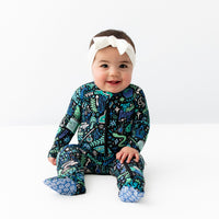 Baby in The Second-Skin Footie Mystic Mama Blue with zipper front and white headband.