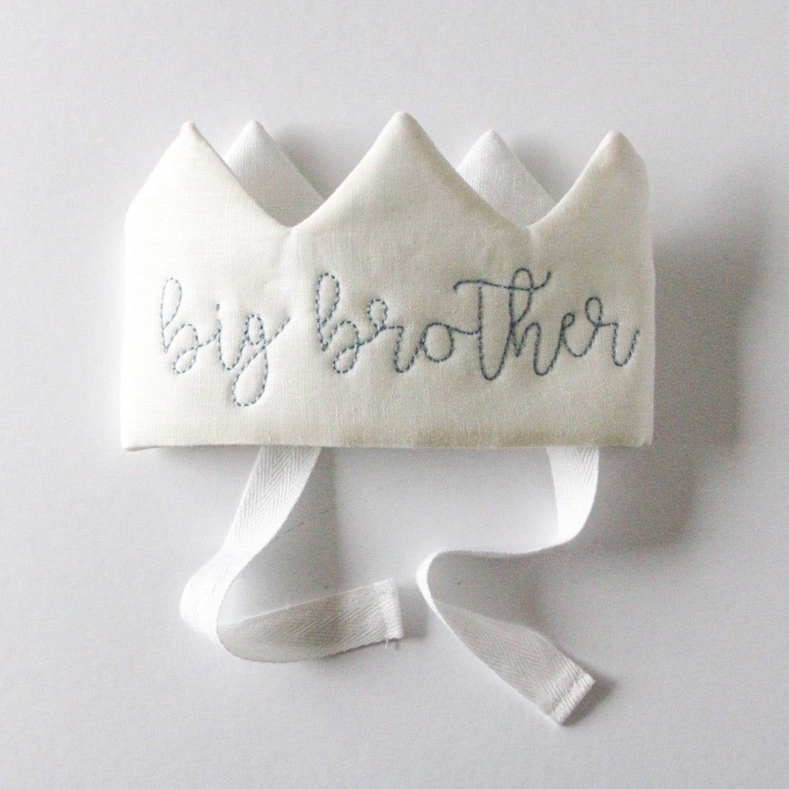 White crown with 'big brother' embroidery on a light gray background