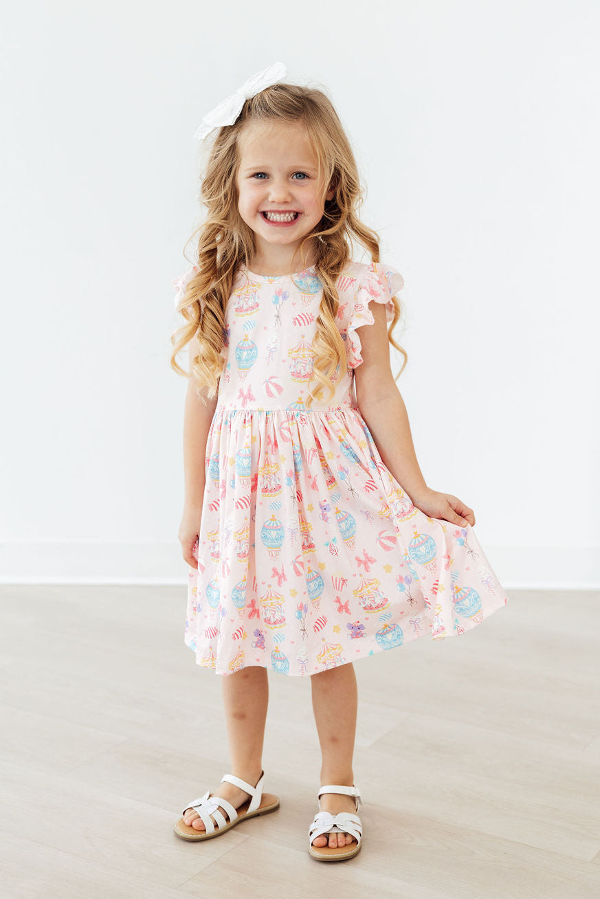 Girl in Off to the Circus Flutter Sleeve Twirl Dress, pink circus-print with flutter sleeves.