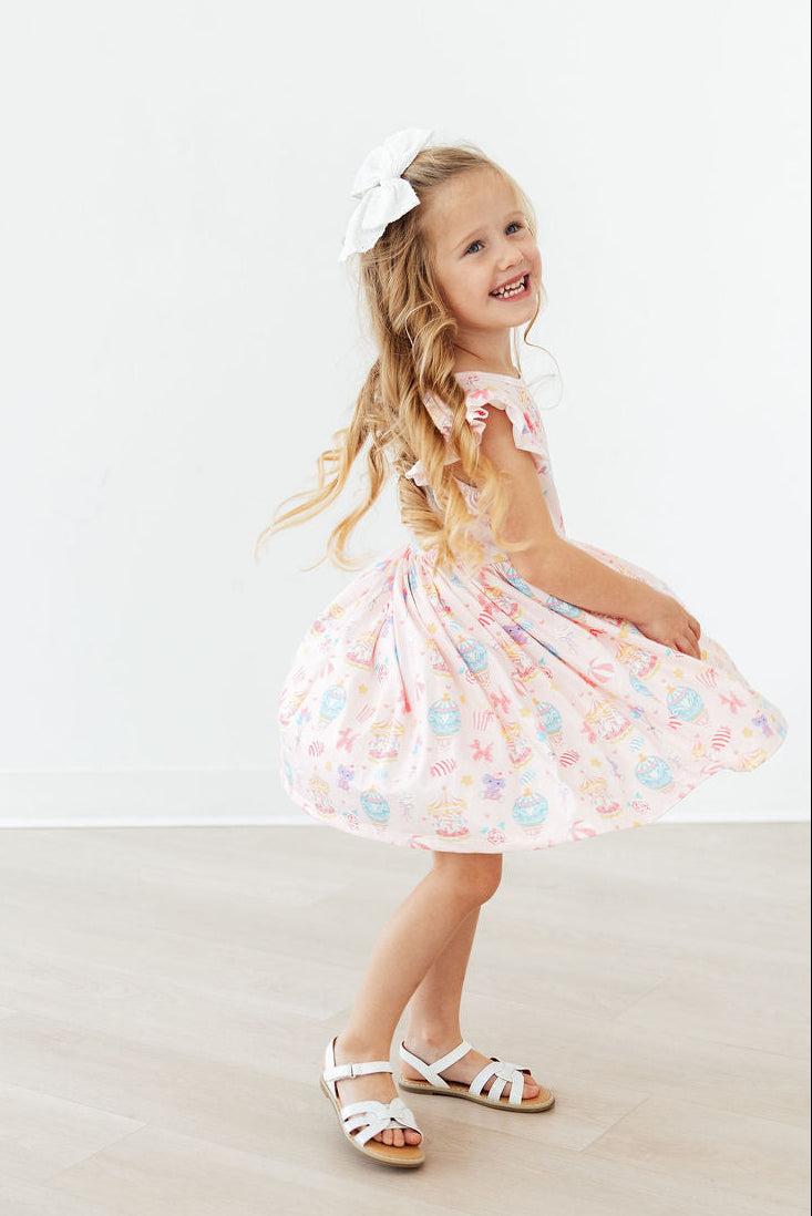Child twirls in Off to the Circus Flutter Sleeve Twirl Dress with a white bow.