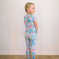 Child wearing The Second-Skin 2-Piece Short Sleeve Pajama in light blue with colorful floral print.