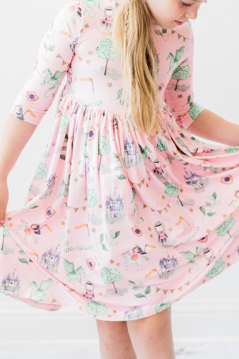 A young girl twirls in the Once Upon a Time 3/4 Sleeve Pocket Twirl Dress by Mila & Rose, revealing its charming design filled with playful elements, creating a delightful scene.