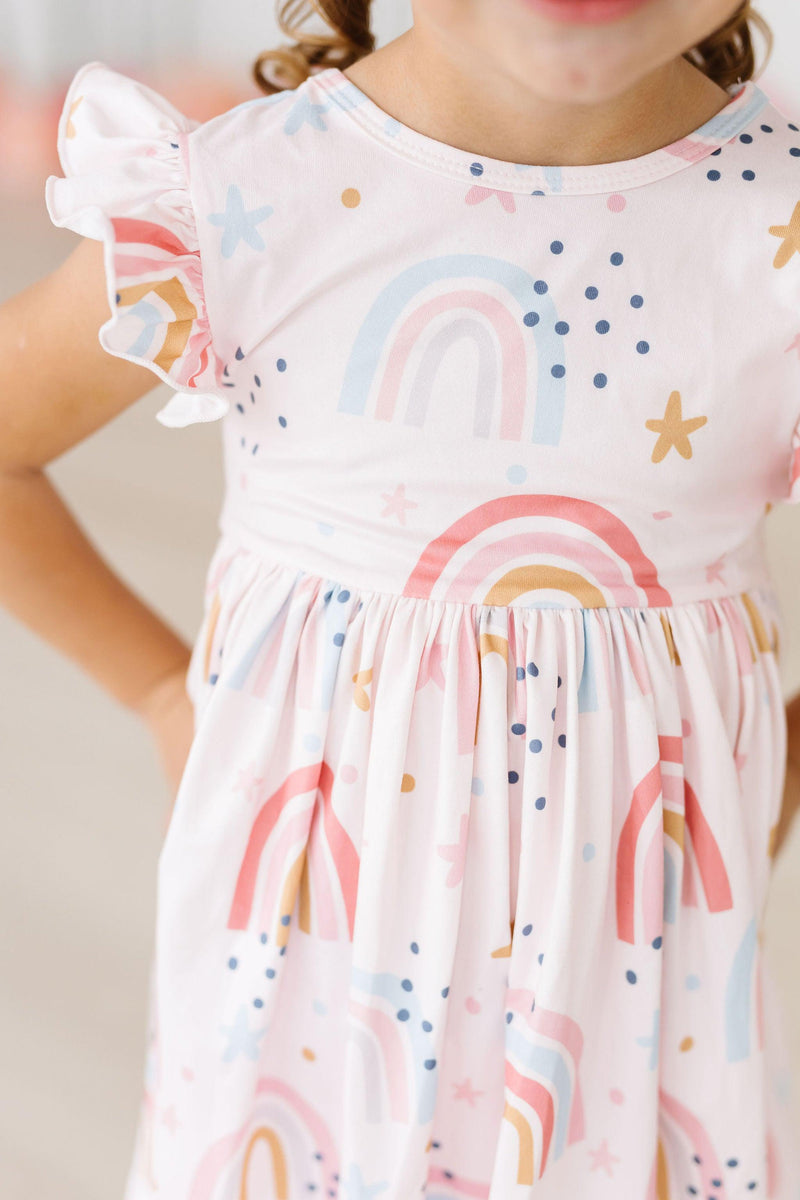 Close-up detail of the Over the Rainbow Flutter Sleeve Twirl Dress by Mila & Rose, highlighting the vibrant rainbow patterns and fun stars that make twirling a delight.