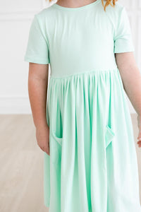 Pastel green short-sleeve pocket twirl dress for girls with a gathered waist and pockets.