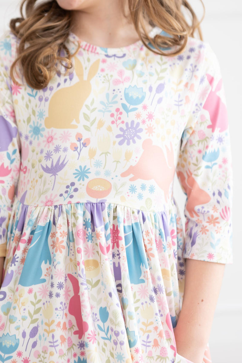 Close-up of a girl in the Pastel Floral Bunnies 3/4 Sleeve Pocket Twirl Dress, featuring the enchanting patterns of bunnies and flowers.