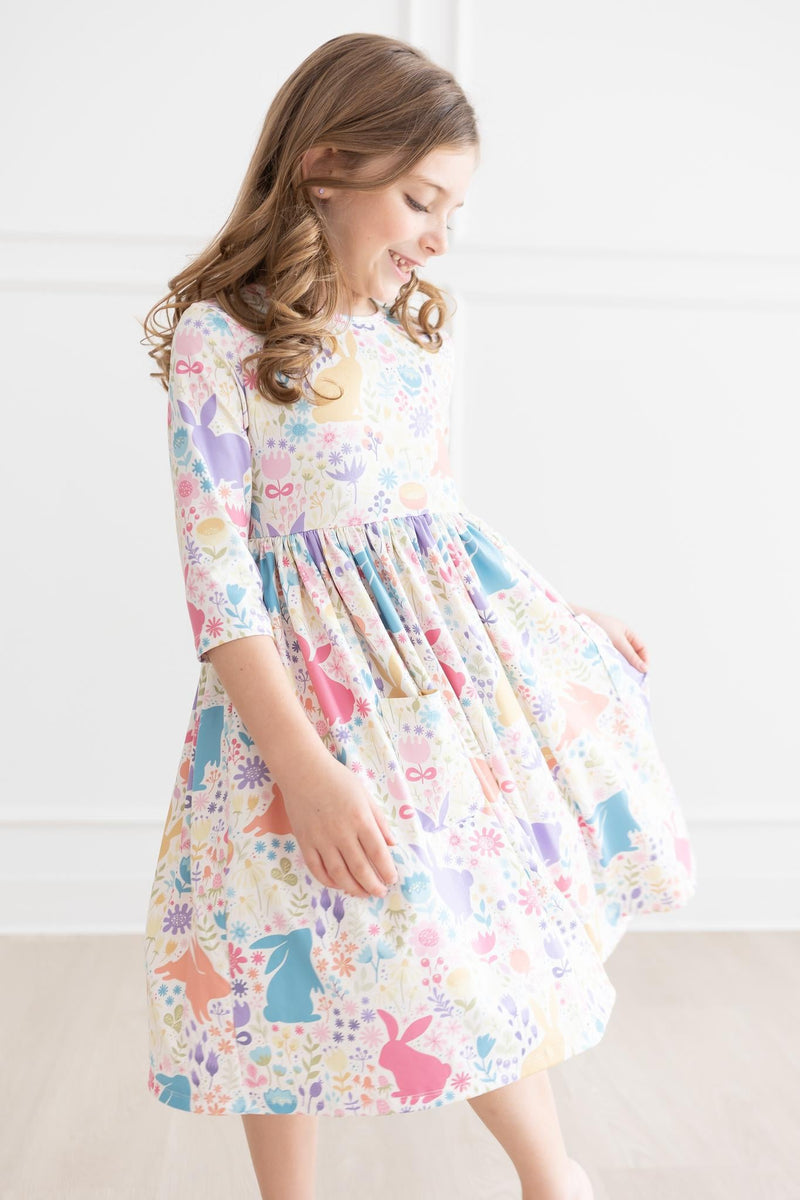A girl spins joyfully in the Pastel Floral Bunnies 3/4 Sleeve Pocket Twirl Dress, emphasizing the twirl-friendly fabric and playful design.