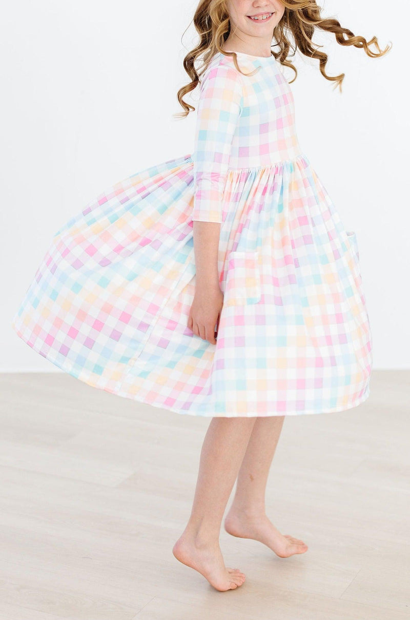 Girl in action, spinning while wearing a Pastel Plaid 3/4 Sleeve Pocket Twirl Dress from Mila & Rose, showcasing the dress's enchanting twirl ability.