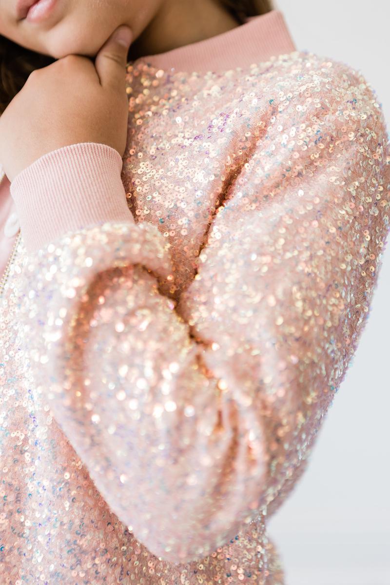 Close-up of a girl in a Peach Sequin Jacket, highlighting the dazzling shimmer and soft materials for little trendsetters.