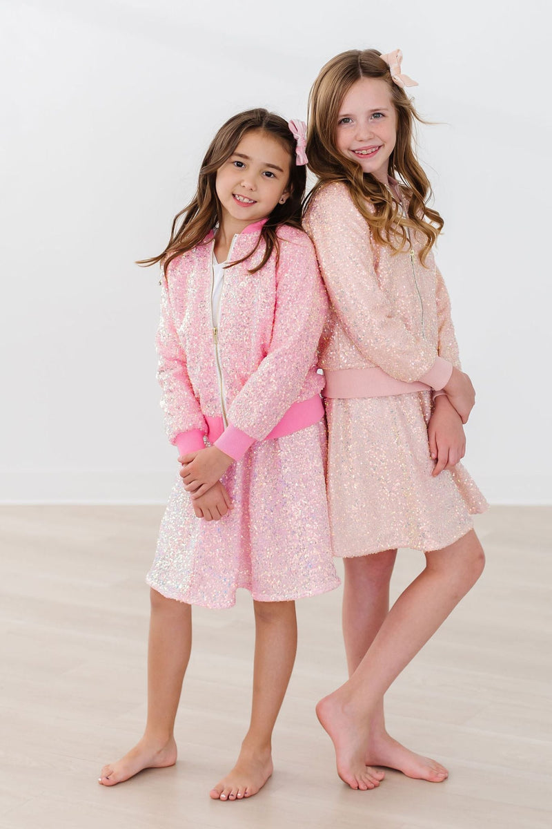 Two girls modeling vibrant Peach Sequin Jackets, exuding joy and friendship, embodying the ultimate chic look for young fashionistas.