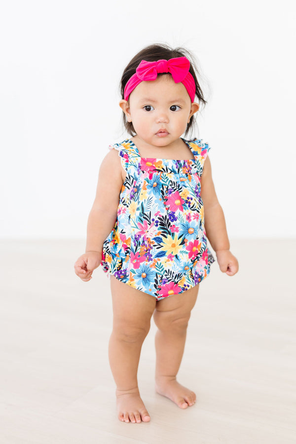 Petal Paradise Ruffle Cross Back Romper on a baby girl with a floral outfit and pink headband.