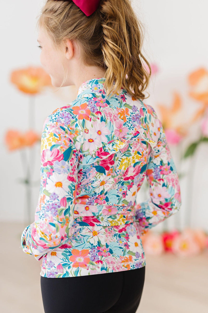 Back view of a girl wearing the Petal Power Full-Zip Ruffle Active Jacket, highlighting the stylish ruffle detail and floral design.