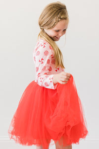 Girl wearing pink peppermint print long sleeve dress with vibrant red tulle skirt, perfect for twirling and play.