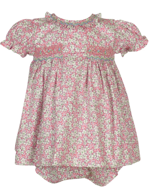 Pink floral smocked dress with white flowers, puff sleeves, and ruffled collar on a child