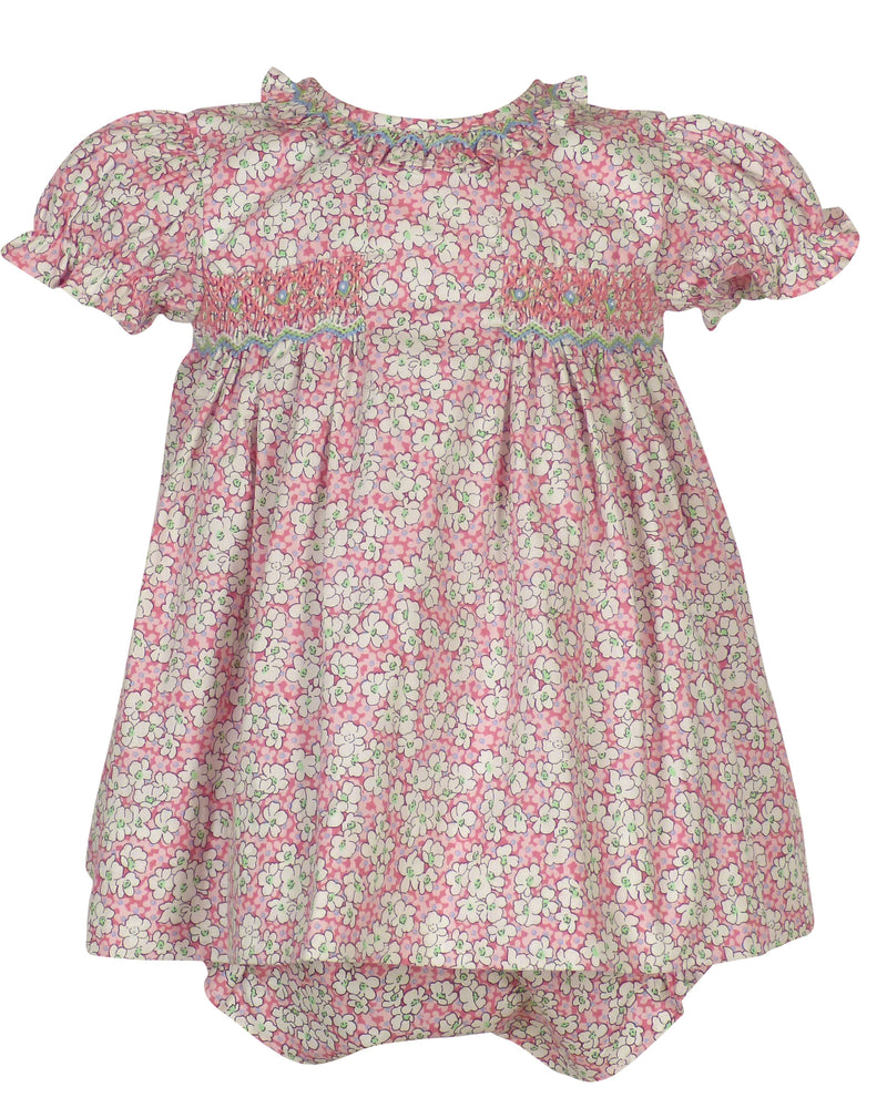 Pink floral smocked dress with white flowers, puff sleeves, and ruffled collar on a child