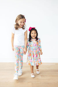 Two girls in pumpkin-print outfits; one wears a Preppy Pumpkins 3/4 Sleeve Ruffle Twirl Dress with ruffles.