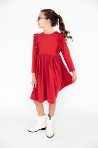 Girl wearing red long sleeve ruffle twirl dress with white cowboy boots, showing off the comfortable twirly skirt.