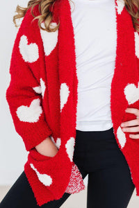 Red fuzzy heart cardigan worn open over a white tee and black leggings for a cozy, stylish look.