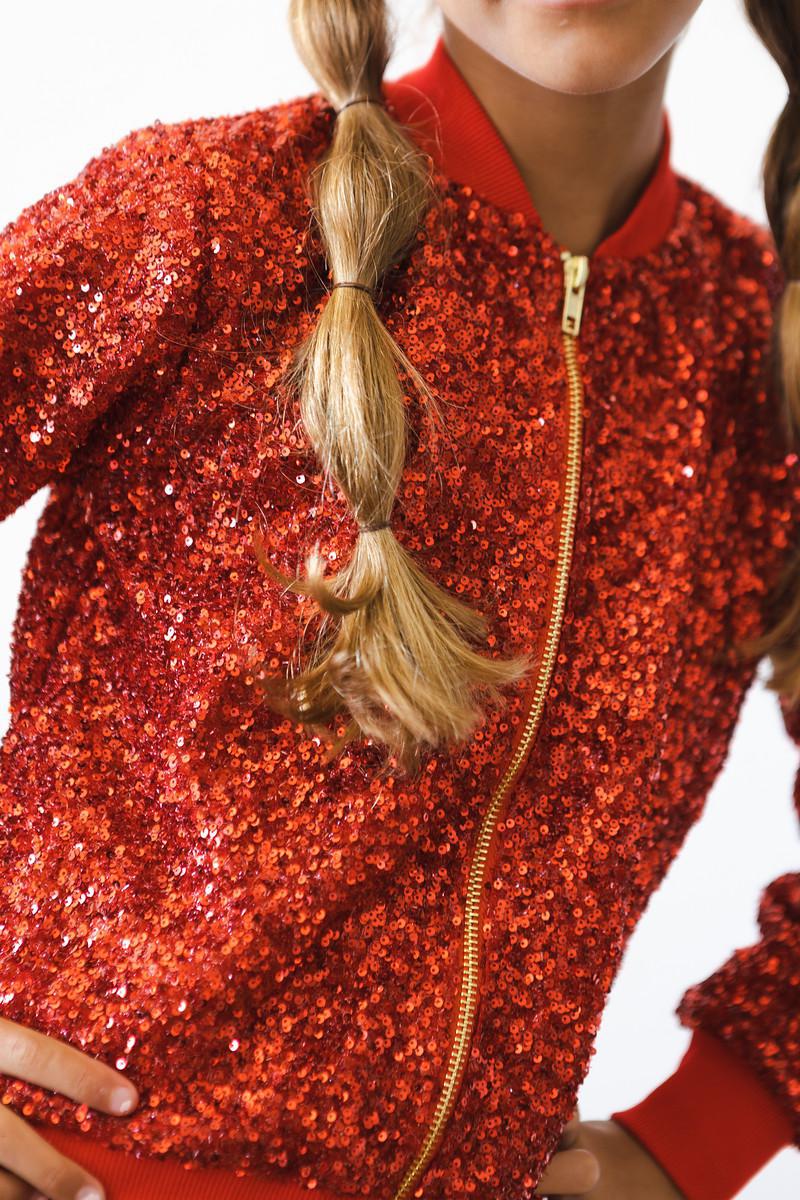 Little girl wearing a stylish Red Sequin Jacket by Mila & Rose, twirling with joy and catching the light with sparkling sequins.