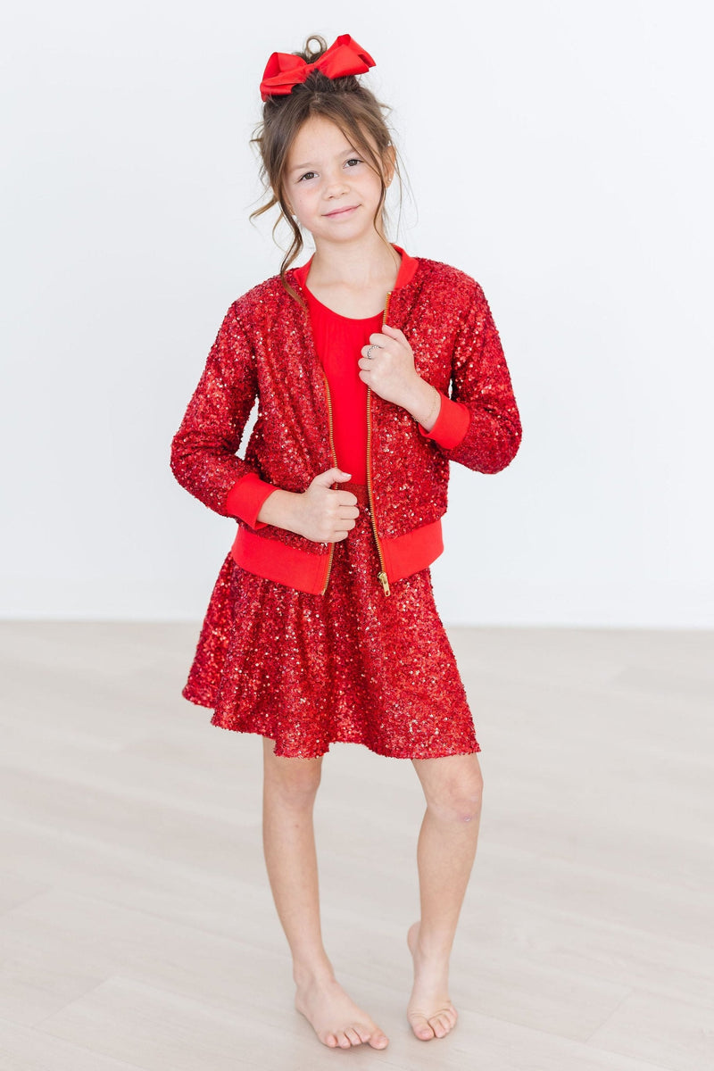 Happy child wearing the Red Sequin Twirl Skort from Mila & Rose with a stylish bomber jacket, showcasing a vibrant and playful look.