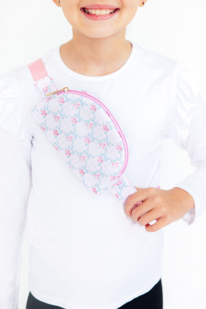 Child wearing a floral and ribbon print belt bag crossbody style. Perfect hands-free accessory for kids to carry essentials during adventures.