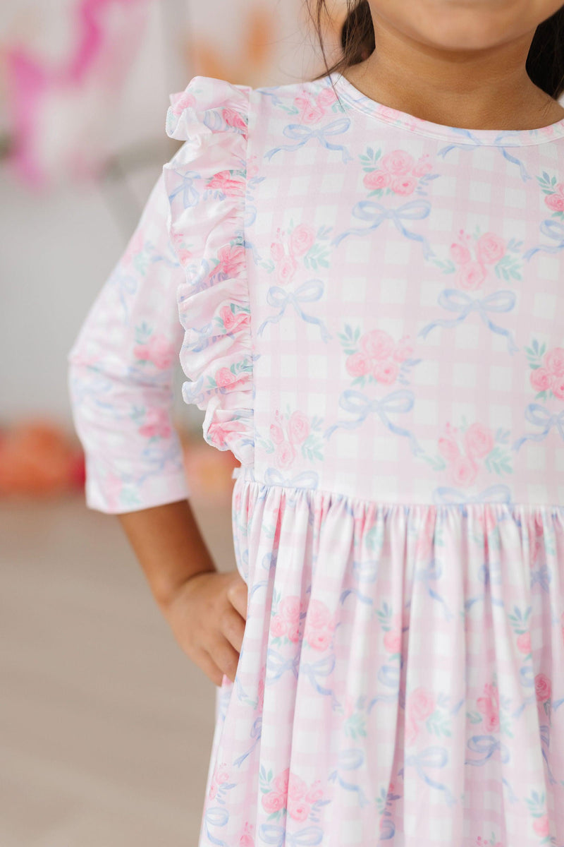 Close-up of the Ribbons & Roses 3/4 Sleeve Ruffle Twirl Dress, highlighting the delicate floral pattern and ruffle sleeve design worn by a joyful child.