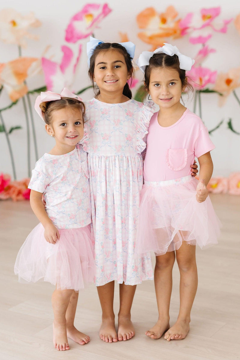 Three cheerful girls in matching outfits, including the Ribbons & Roses 3/4 Sleeve Ruffle Twirl Dress, posing together with bright smiles and fun tulle skirts.