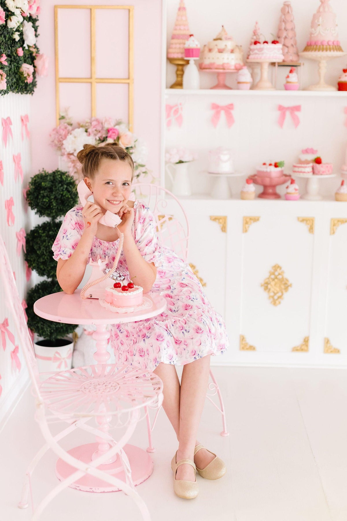 Rose Garden Smocked Ruffle Dress on a smiling girl in a pink floral outfit; stretchy smocked bodice and ruffle skirt.