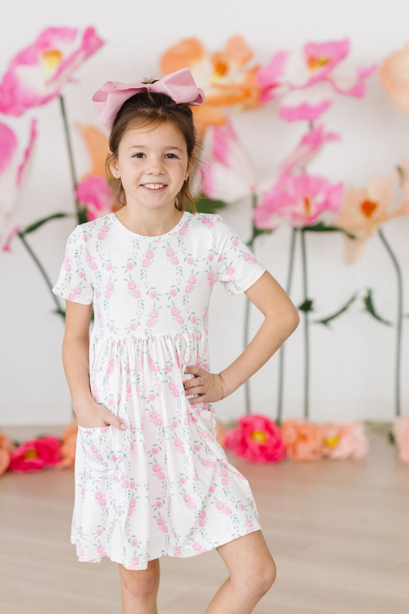 Brightly colored Rosie Posie S/S Pocket Twirl Dress by Mila & Rose on a clothing rack, highlighting its delightful pattern ready for fashion adventures.