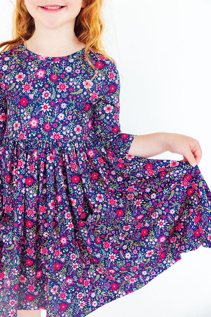 Girl wearing Flower Farm 3/4 Sleeve Pocket Twirl Dress in navy floral print with a full twirl skirt.