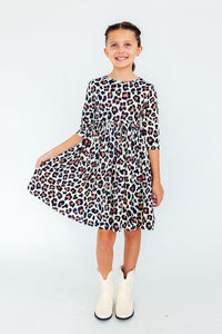 Girl twirling in leopard print 3/4 sleeve pocket dress with white cowboy boots. Comfortable and easy to wash kids fashion.