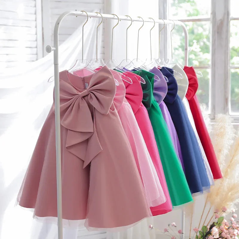 Sari-Elle Elegant Party Dress with Large Bow on a rack in 8 colors for girls aged 4–6.