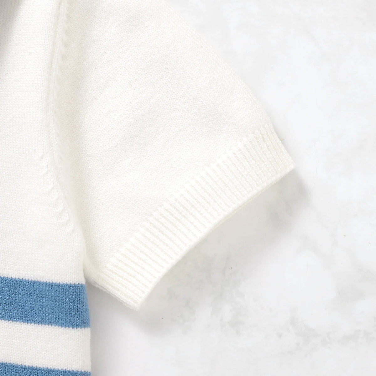 Close-up of a white towel with blue stripes on a light gray background