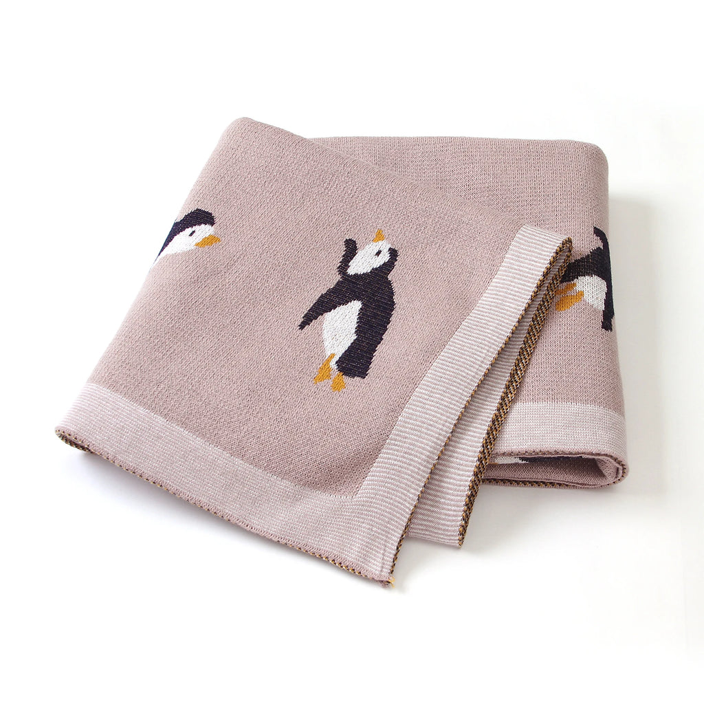 Little Penguins Children's Knit Blanket elegantly folded, showcasing adorable penguin designs - a cozy choice for any child.
