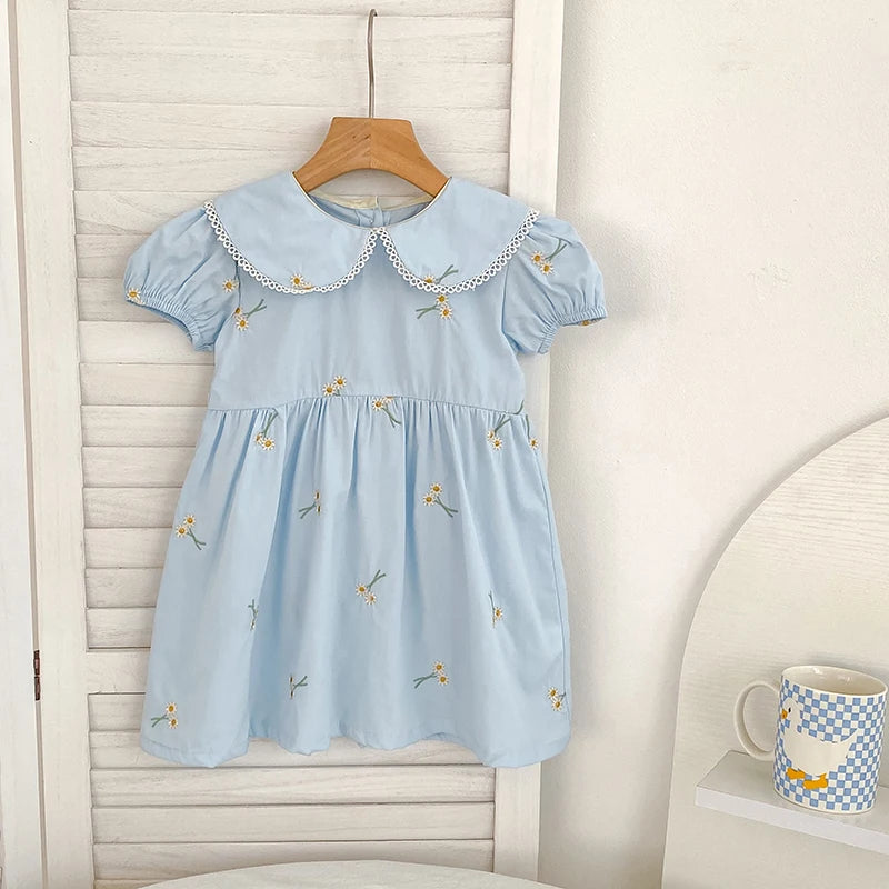'Sweet Lydia' Little Girl's Dress in sky blue featuring embroidered daisies and a classic Peter Pan collar, perfect for ages 2 to 6.