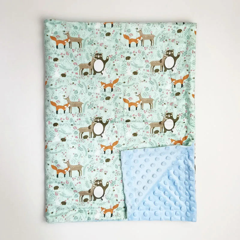 Soft minky baby blanket featuring forest animal print with foxes and deer, alongside a textured light blue dotted reverse side.