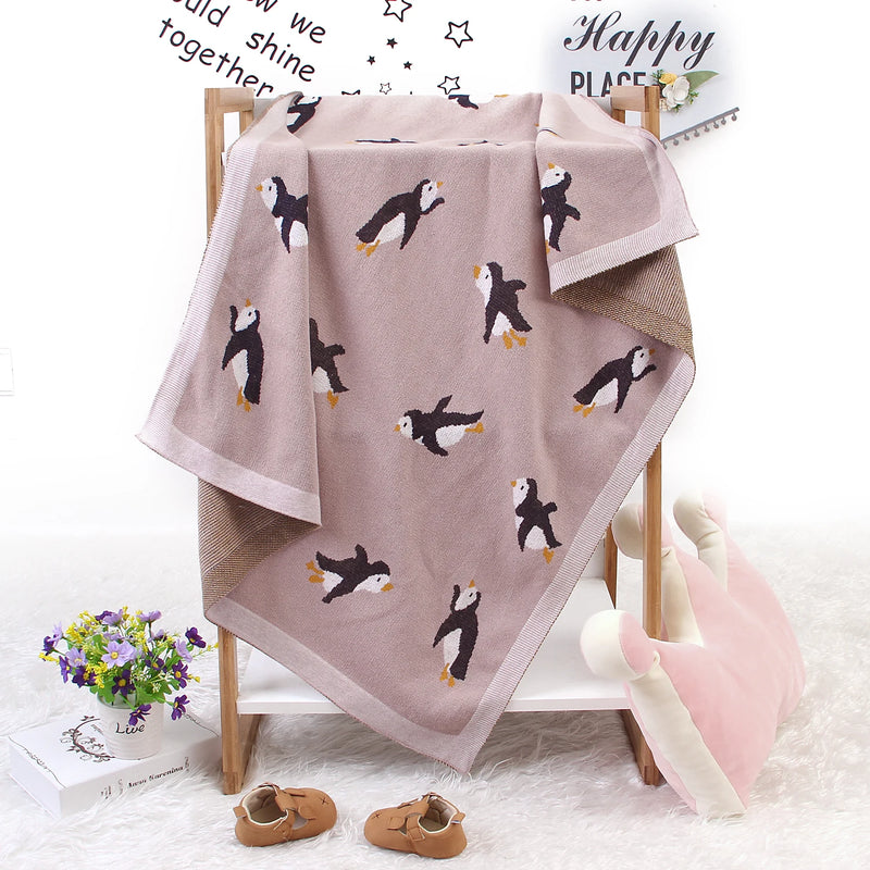 Little Penguins Children's Knit Blanket beautifully displayed on a stand, featuring playful penguin patterns perfect for nurturing imagination.