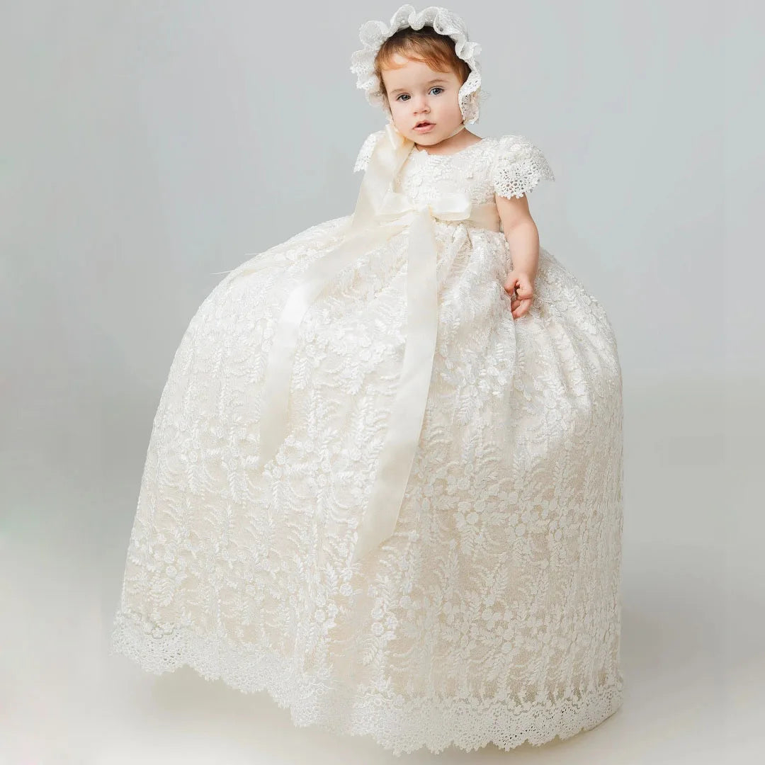 Elegant ivory full长度 lace flower girl gown with matching bonnet, satin ribbon bow, and floral appliques for baptism or wedding.