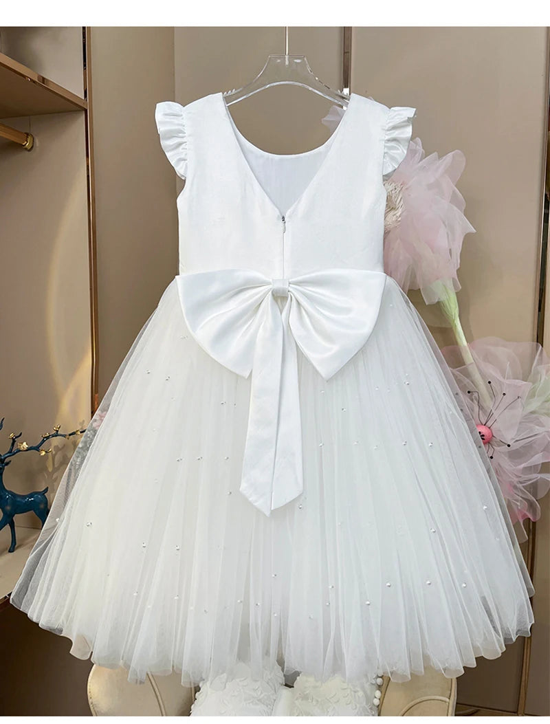 A pink 'Chantelle-Elise' V-Back Occasion Dress, styled elegantly with tulle and a large bow, ideal for a memorable celebration.