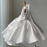 White dress on a wooden hanger against a neutral background