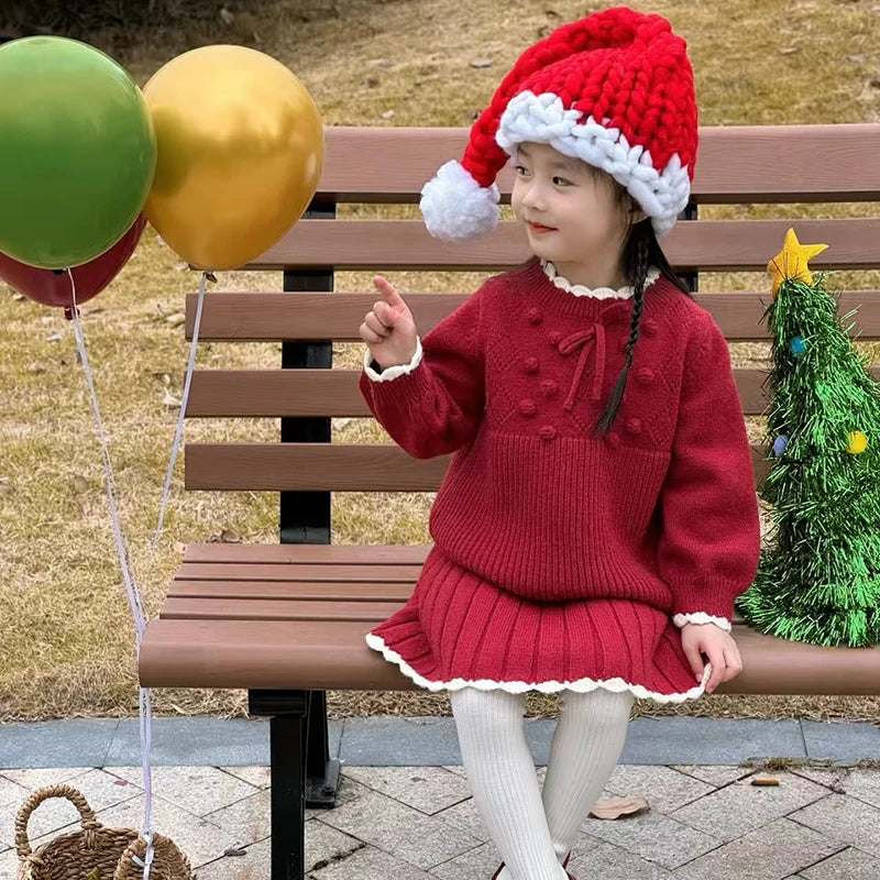 Festive Anna Knit Skirt Set for Girls worn by a young girl outdoors, featuring a vibrant red pullover and skirt, great for winter celebrations.