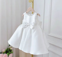 White satin knee-length girls' formal dress with bow at the waist, sleeveless, princess silhouette.