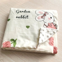 White lightweight Minky baby blanket featuring a garden rabbit, hearts and pink flowers print.