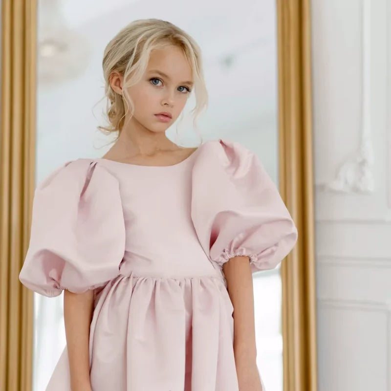 Close-up of a young girl modeling the 'Arora' Puffed Sleeved Party Dress, highlighting the elegant puffed sleeves and scoop neckline.