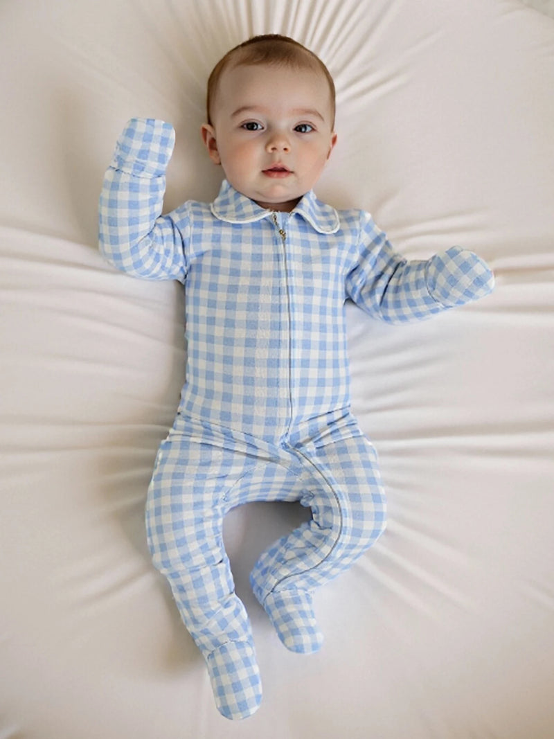 Baby relaxing in the 'Baily' Checked Footie in Boca Blue, laying comfortably on a soft surface.