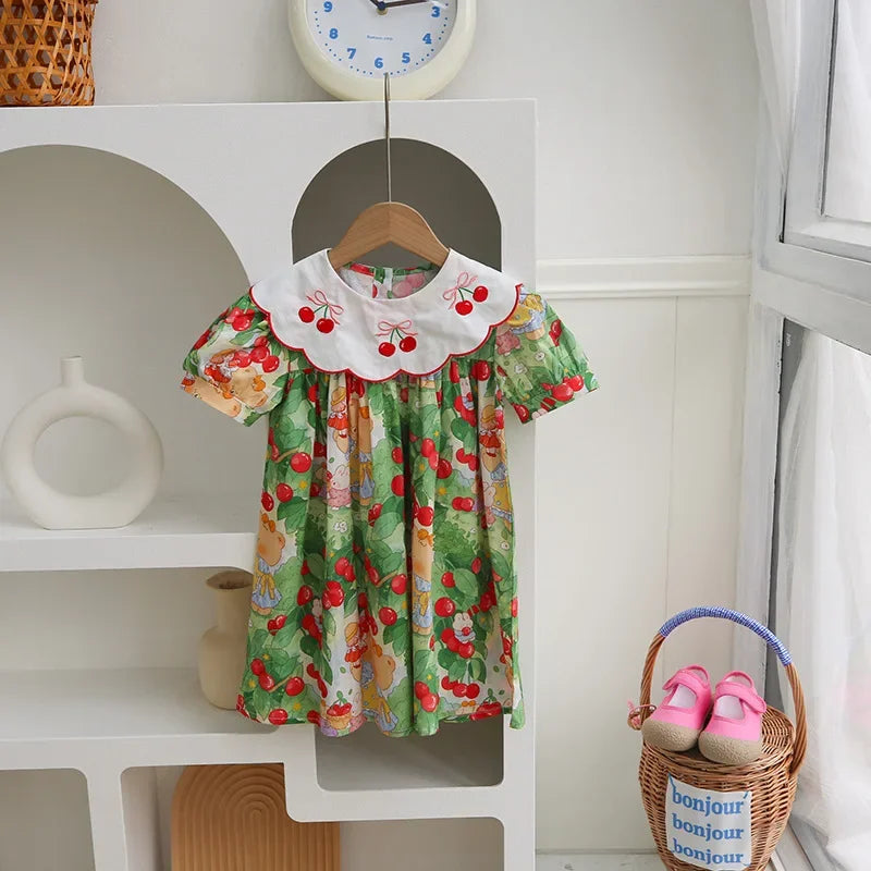 A Very Cherry Day Embroidered Dress displayed in a bright setting, highlighting the vibrant cherry print dress and its playful design.