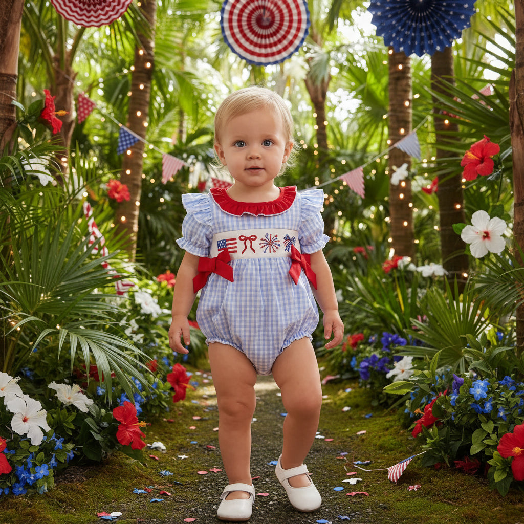 Baby in a patriotic outfit standing on a wooden floor with decorative flags in the background.